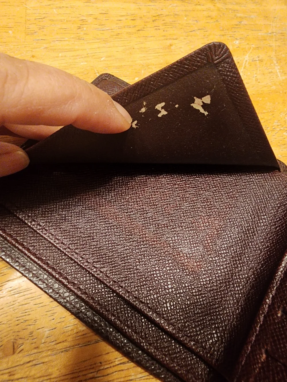 burgandy Louis Vuitton Taiga leather bifold wallet featuring a debossed LV